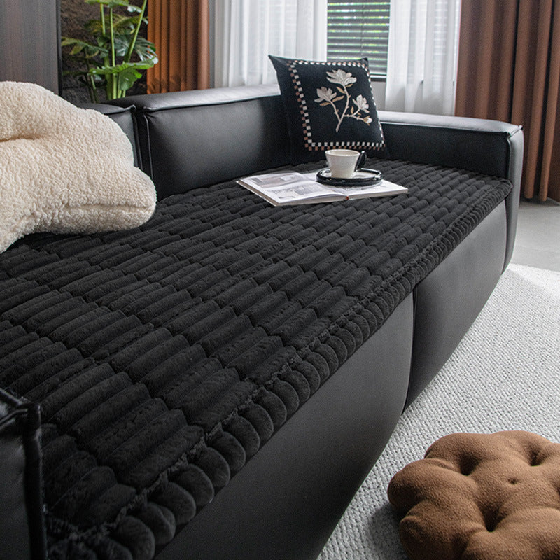 Black plush dog bed mat used as a sofa cover at home