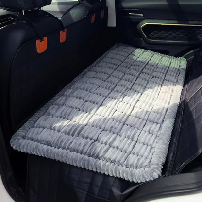 Grey plush non-slip dog bed mat laid flat on a black hard bottom back seat extender in an SUV